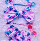 Foto de cima mostrando o conjunto de biquíni rosa do Stitch estendido sobre um tapete peludo branco.