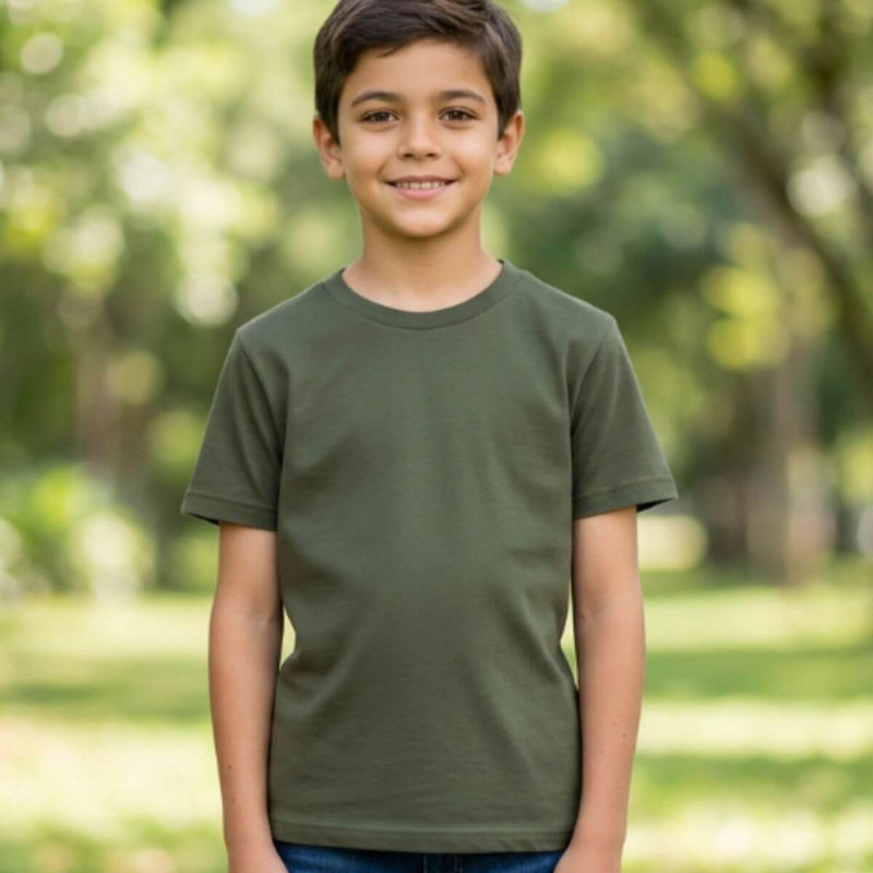 Menino feliz ao ar livre usando camiseta infantil verde militar básica e calça jeans.