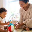Bebê feliz descobrindo novas texturas e cores com brinquedo educativo ao lado da mãe.