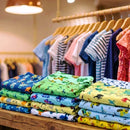 Pilhas de cuecas infantis dobradas em prateleira de madeira, com estampas de dinossauros, robôs e animais