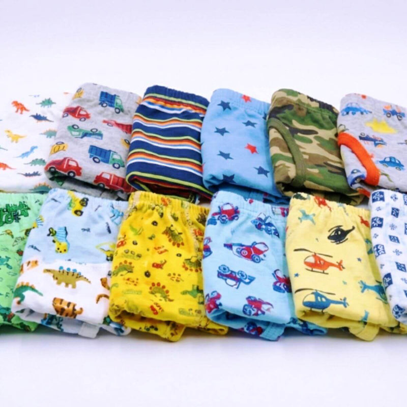 Duas fileiras de cuecas infantis dobradas exibindo estampas variadas de carrinhos, caminhões, dinossauros e listras