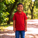 Infográfico de moda infantil premium detalhando gola canelada e bordado tom sobre tom em polo vermelha