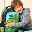 Menino pronto para a escola segurando mochila de carrinho tema video game no parque