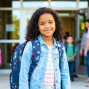 estudante com mochila preta caminhando em ambiente educacional ao ar livre, jovem estudante em área externa, adolescente com mochila escolar sorrindo
