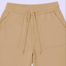 Frente de short infantil bege de moletinho mostrando os bolsos grandes e o cordão de ajuste.