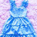 Frente de vestido de menina modelo três marias com saia rodada em camadas e estampa floral delicada.